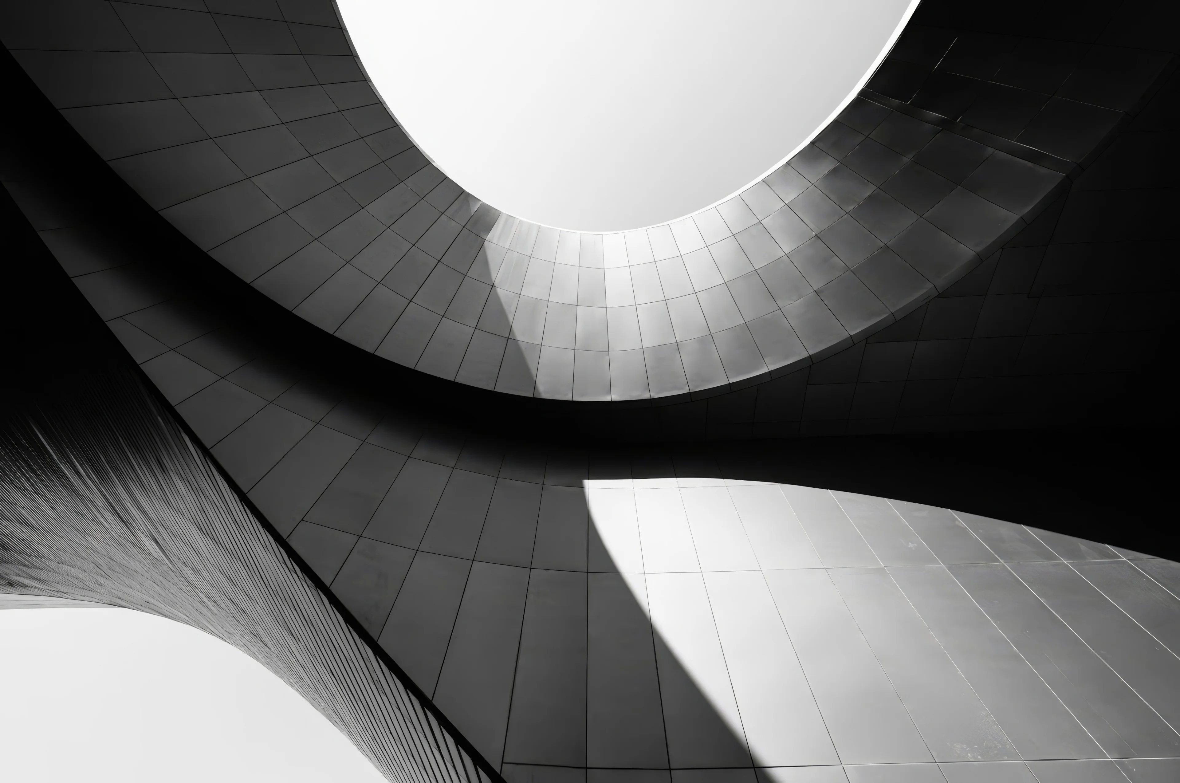 A curved white building against a dark sky, in black and white.