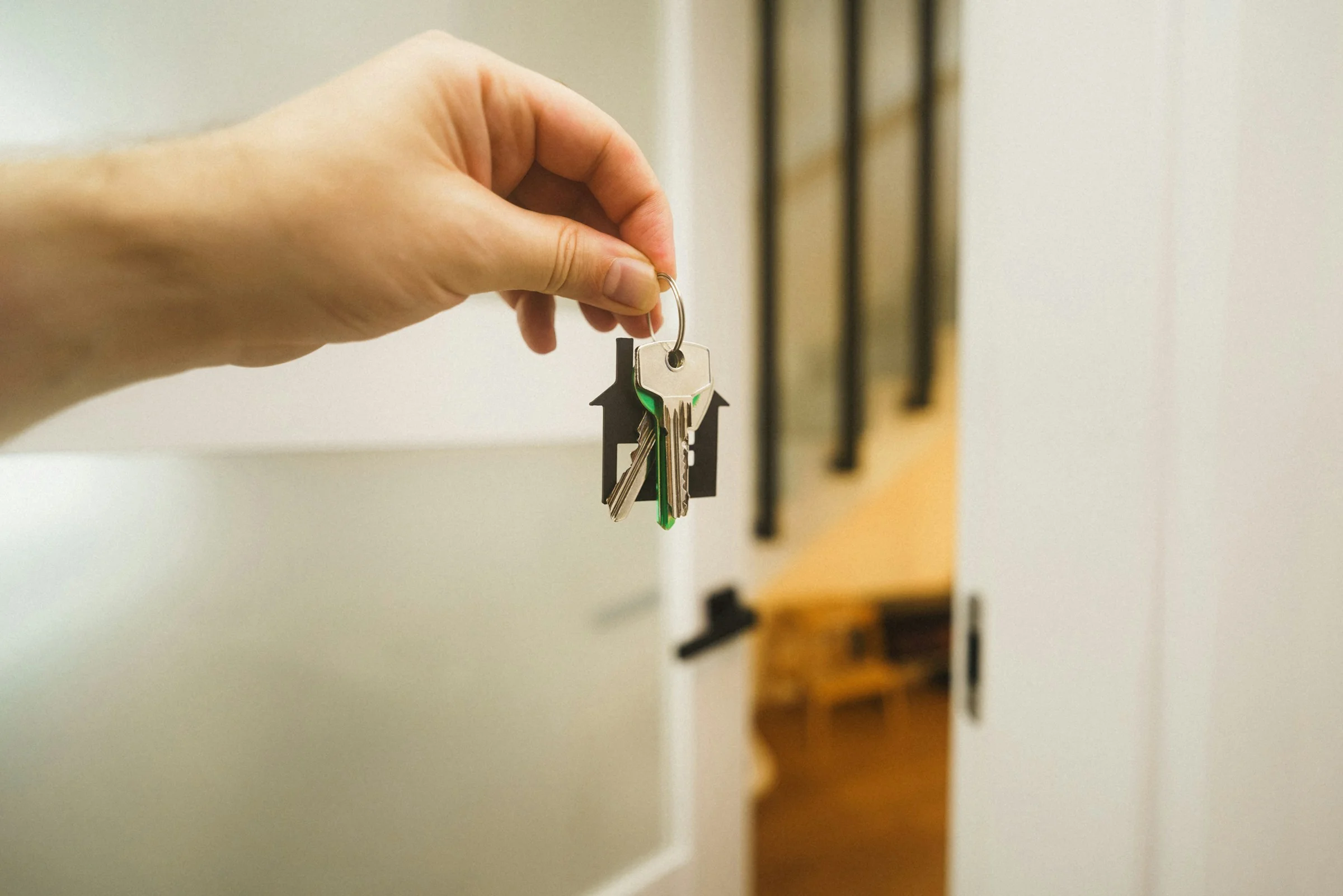 A hand holding a set of house keys at an open door.
